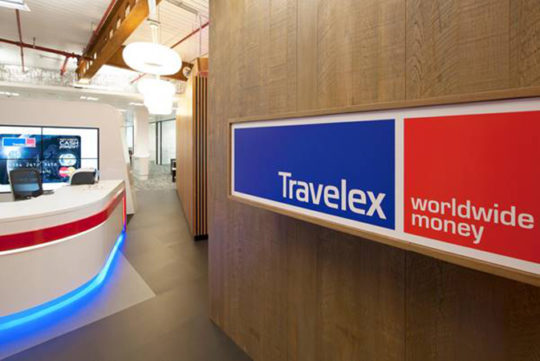 Travelex sign on a wooden wall with reception desk in the background.