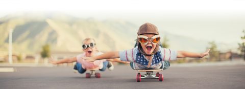 Two boys laying on skateboards with funny goggles